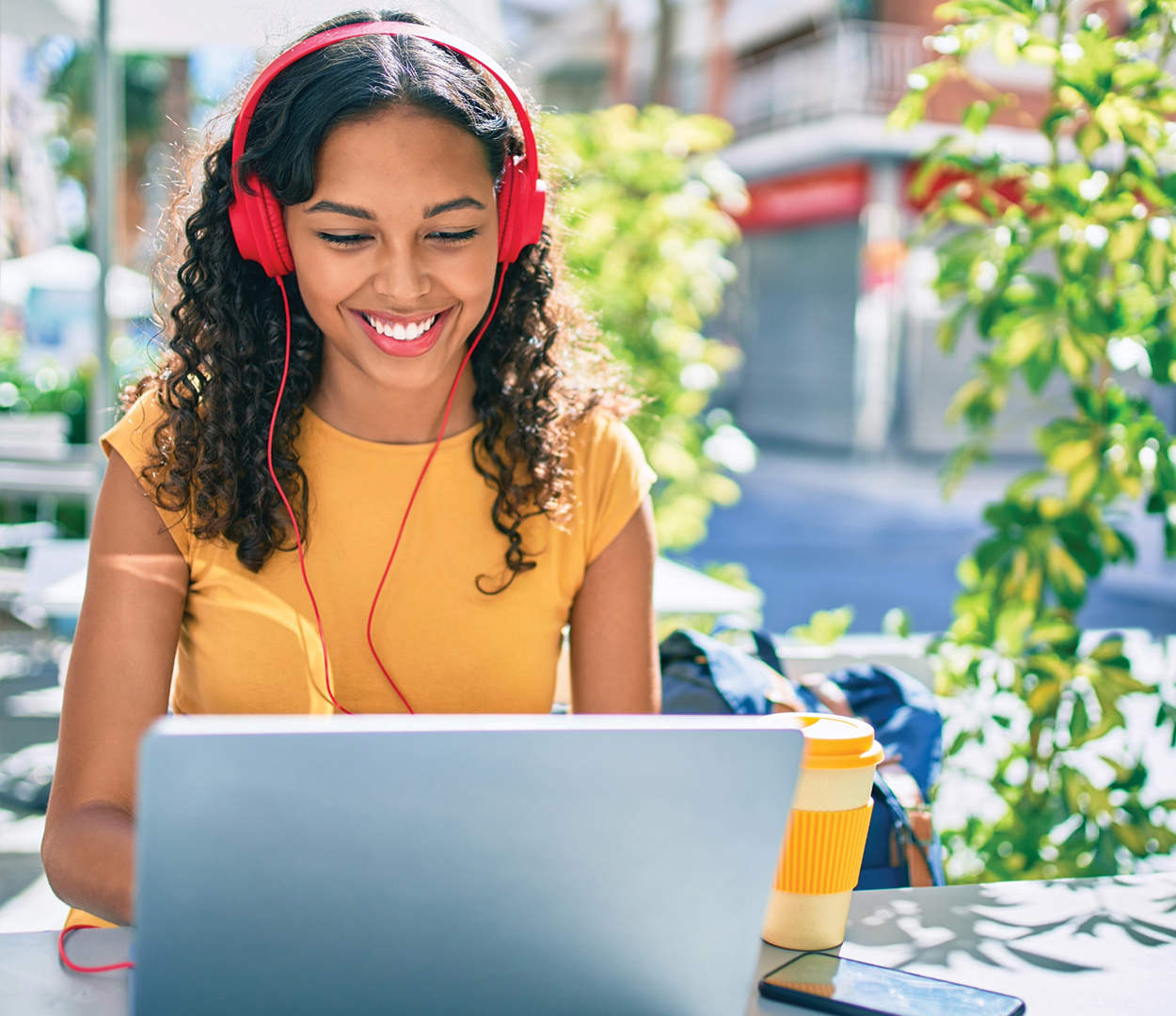 Female high school student with headphones using a laptop.
