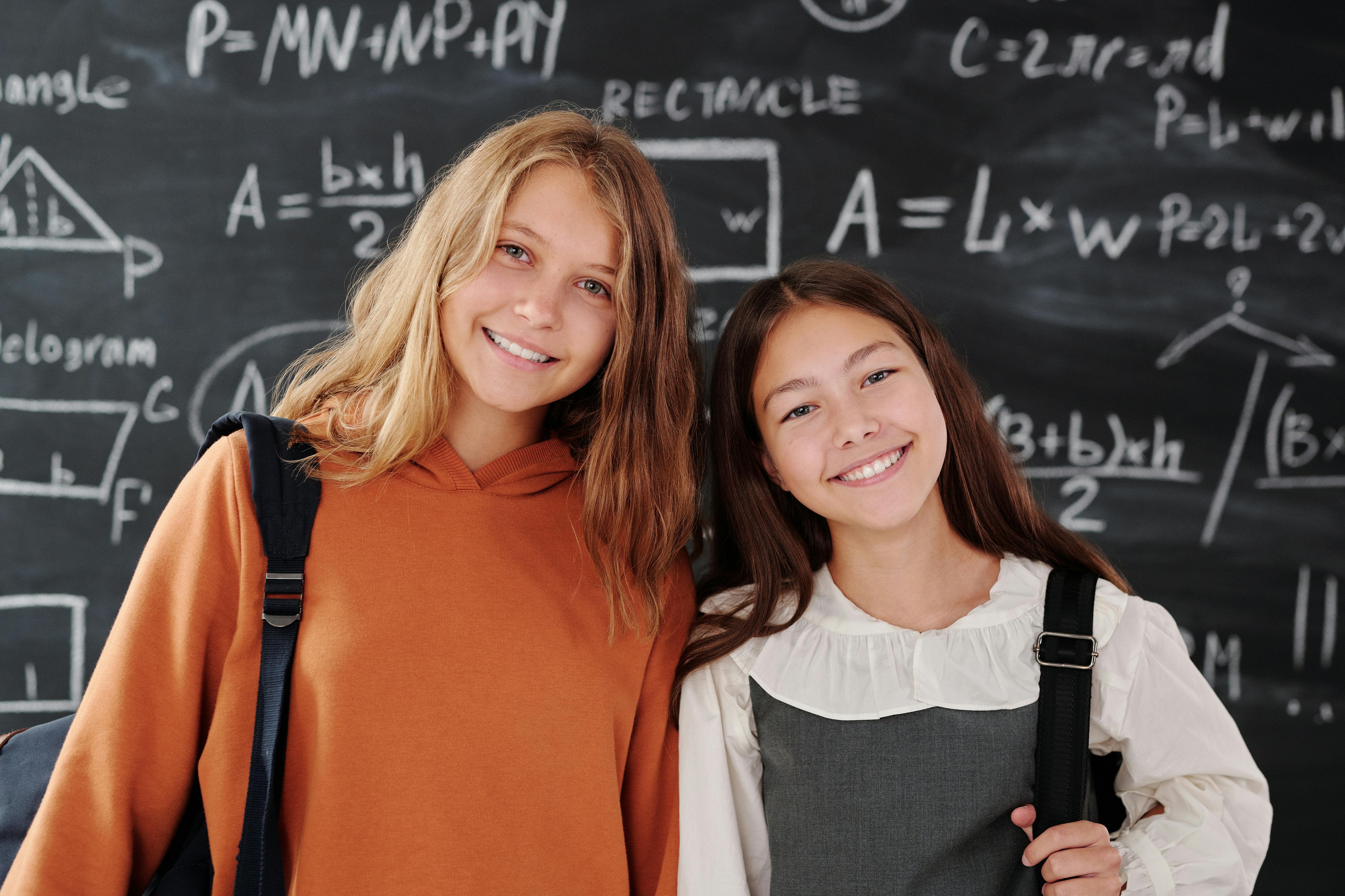 Middle school girls in a classroom in front of a chalk board.