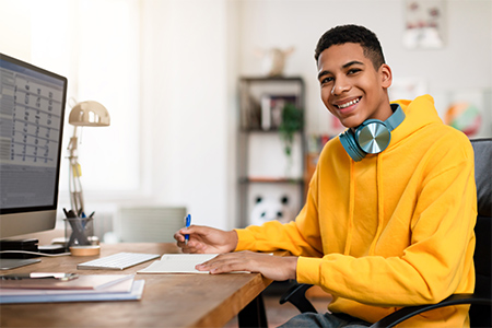 Student by computer writing notes